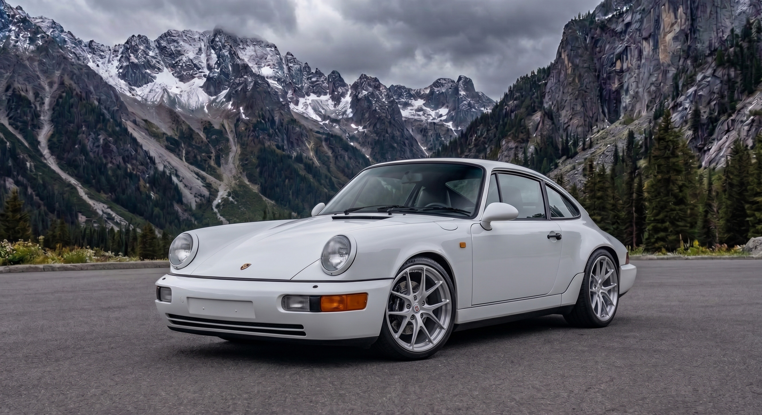 White Porsche 964 parked before a snow-capped mountain range