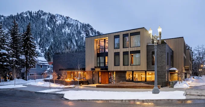 Boutique hotel in Aspen at dusk with a snow-capped mountain behind it