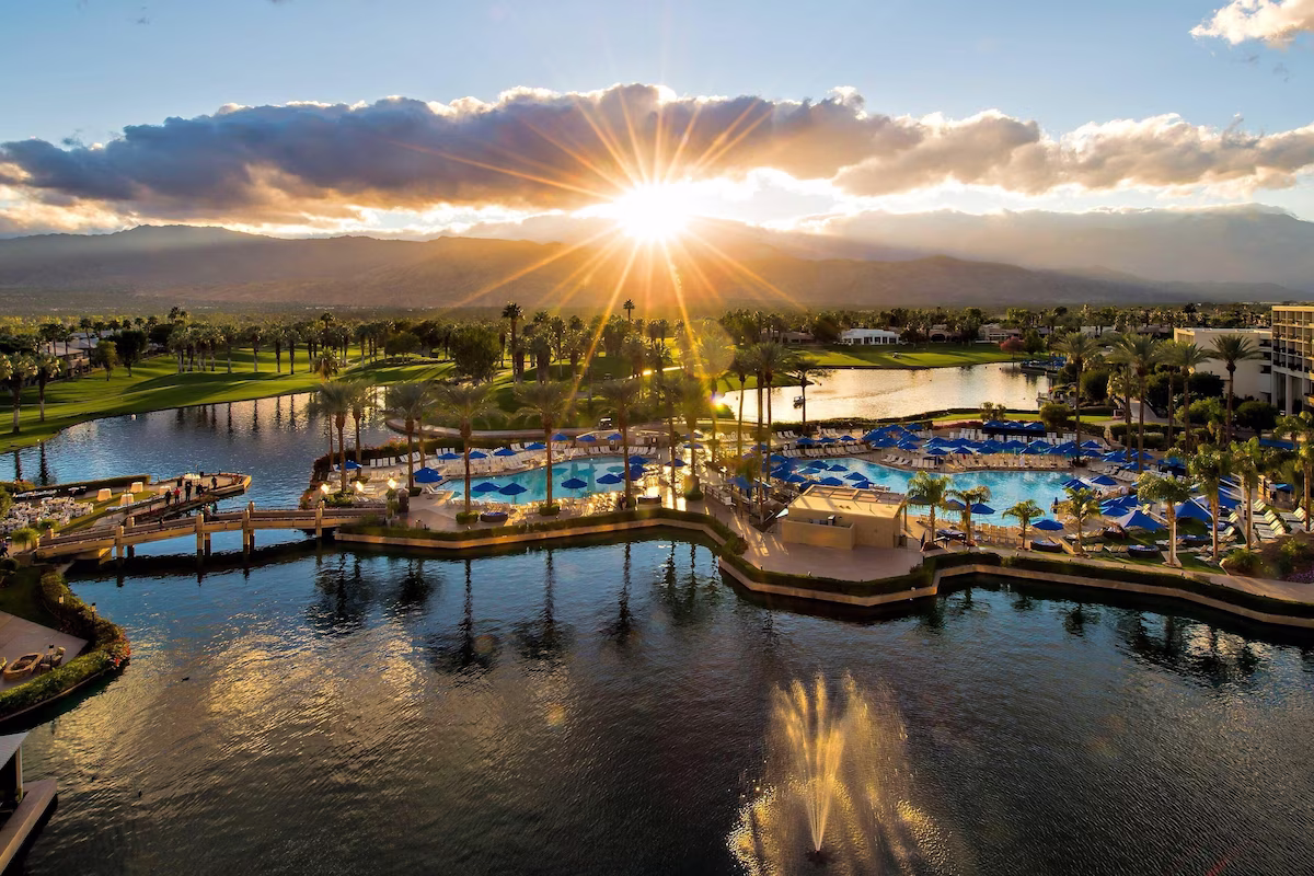 Aerial view of a desert resort with lagoon pools at sunset